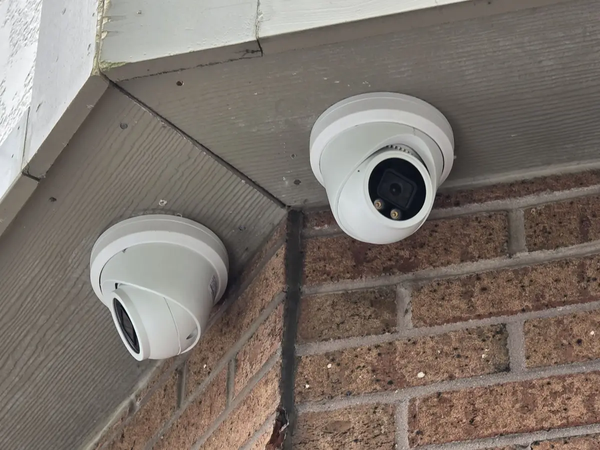 Two turret cameras covering a plaza walkway from the soffit corner