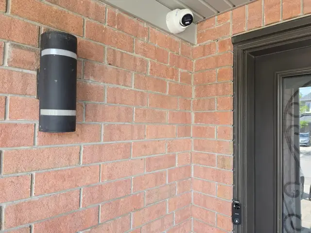 Turret camera covering a front entrance beside the porch light