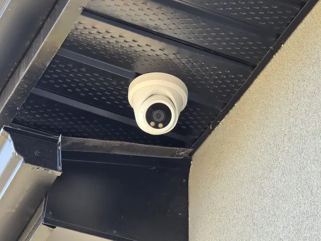 Turret camera under a black soffit on a stucco house