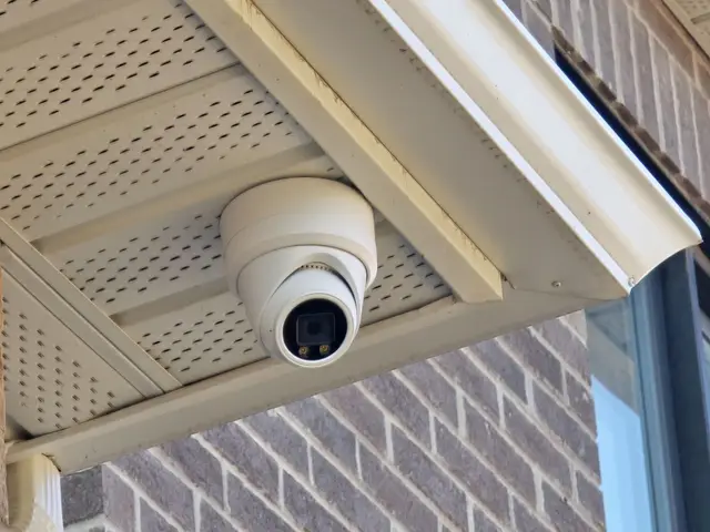 Turret camera mounted in the soffit over a brick wall