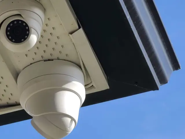 Two cameras mounted under a house soffit against a blue sky