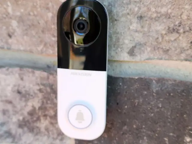 Video doorbell mounted on stone cladding beside a front door